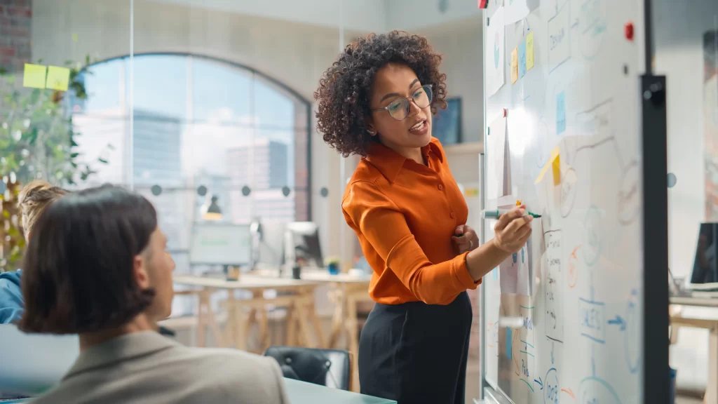 Woman drawing on white board in office space